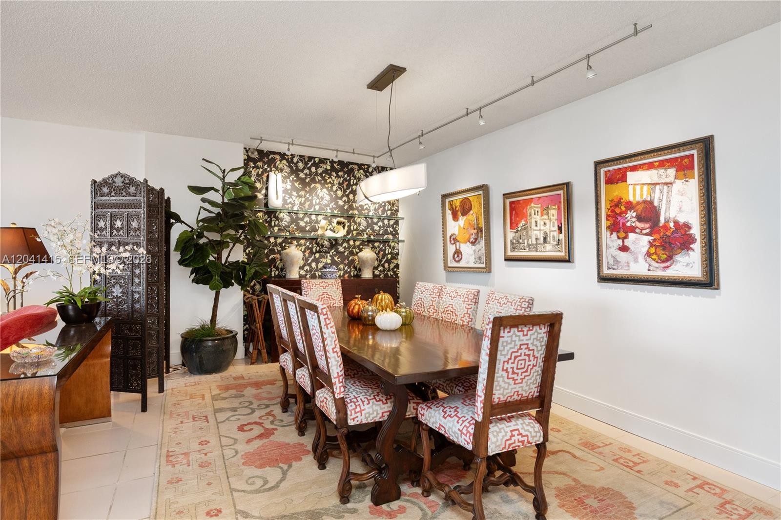 A dining room features a wooden table, patterned chairs, wallpapered accent wall, and track lighting — 1581 Brickell Ave # 903, Miami FL 33129, MIAMI, FL