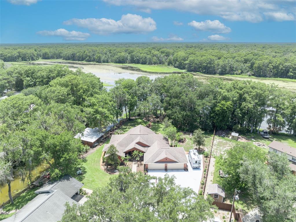 An aerial view shows a house with a multi-gabled roof near a lake and trees — 4885 CR 307, LAKE PANASOFFKEE, FL