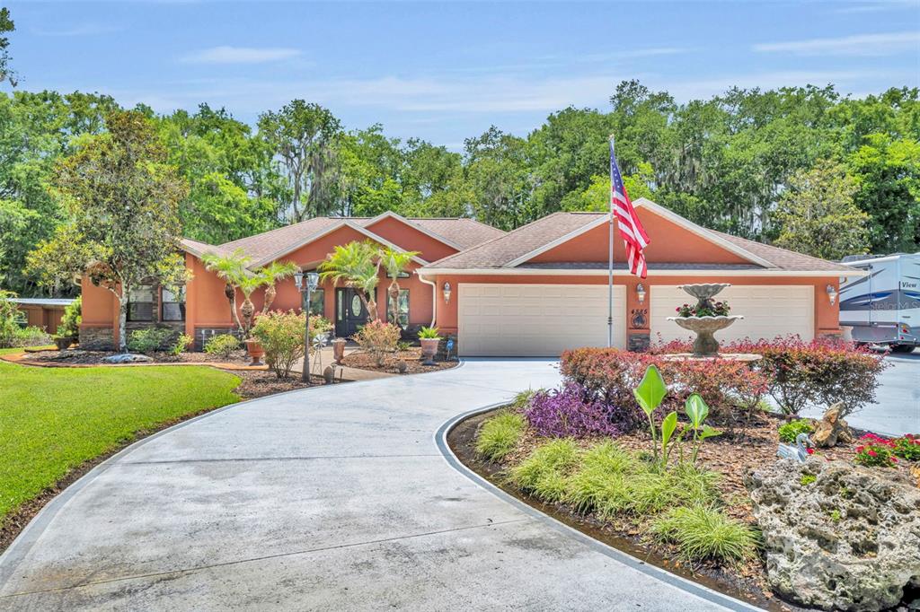 A single-story house with a terracotta exterior, a curved concrete driveway, and an American flag — 4885 CR 307, LAKE PANASOFFKEE, FL