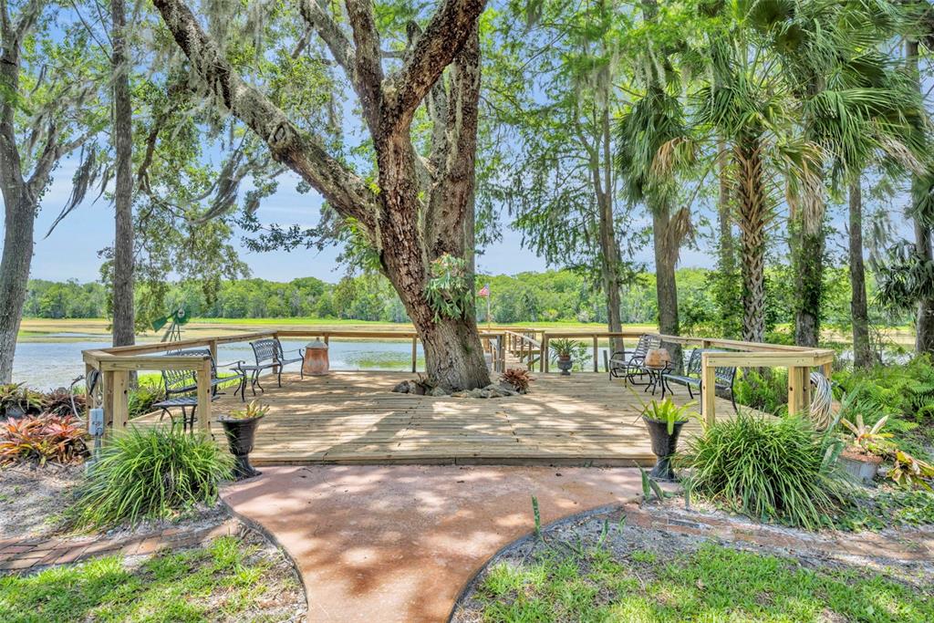 A wooden deck built around a large tree overlooks a marshy waterfront area — 4885 CR 307, LAKE PANASOFFKEE, FL