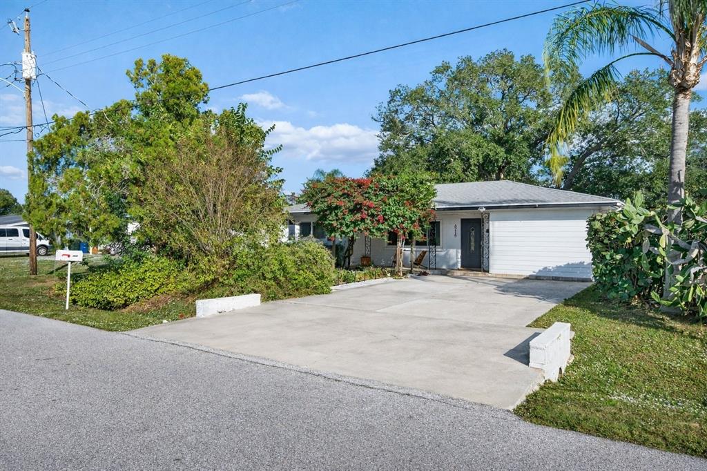A single-story house with a concrete driveway, white siding, and a palm tree — 6215 RODGERS AVENUE, SARASOTA, FL