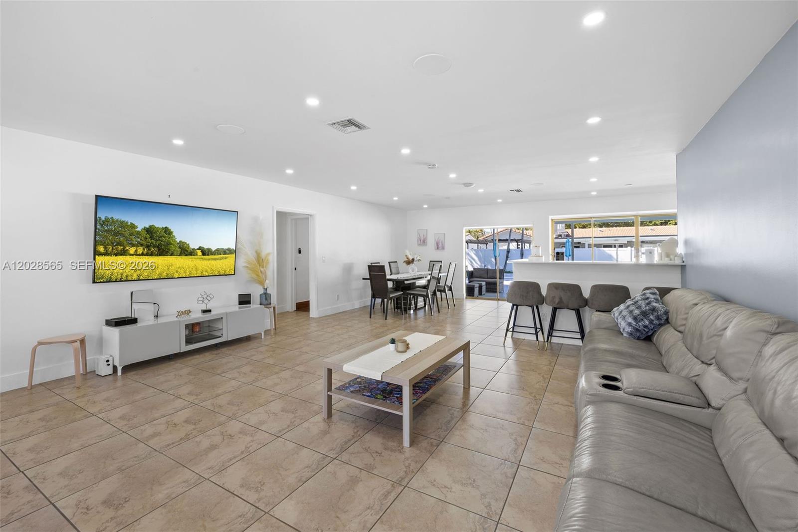 An open-concept living and dining area features tile flooring, a large television, and bar seating — 3460 N 46th Ave, Hollywood FL 33021, HOLLYWOOD, FL