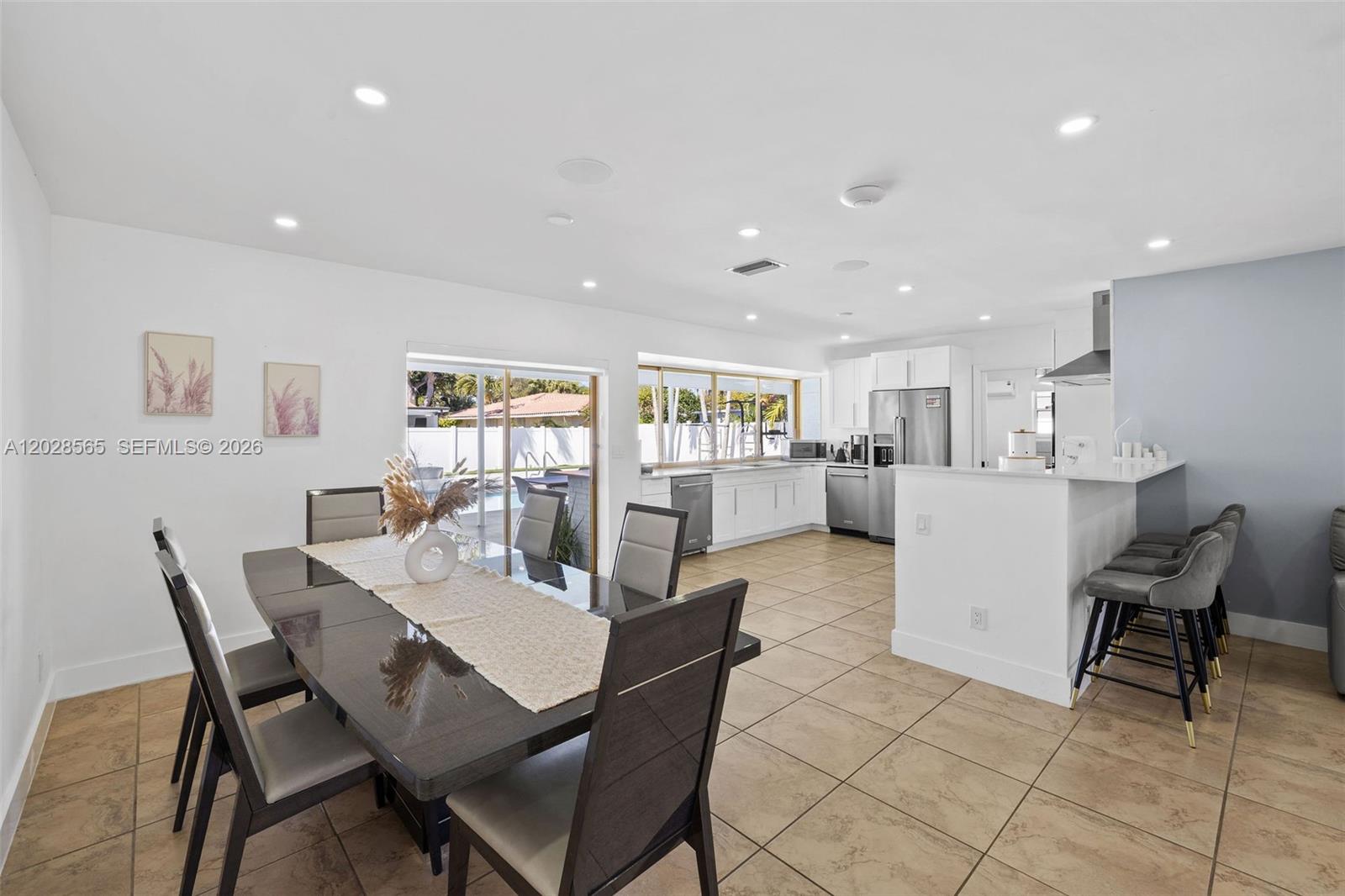 A dining area and kitchen feature tile floors, white cabinetry, and a sliding glass door — 3460 N 46th Ave, Hollywood FL 33021, HOLLYWOOD, FL