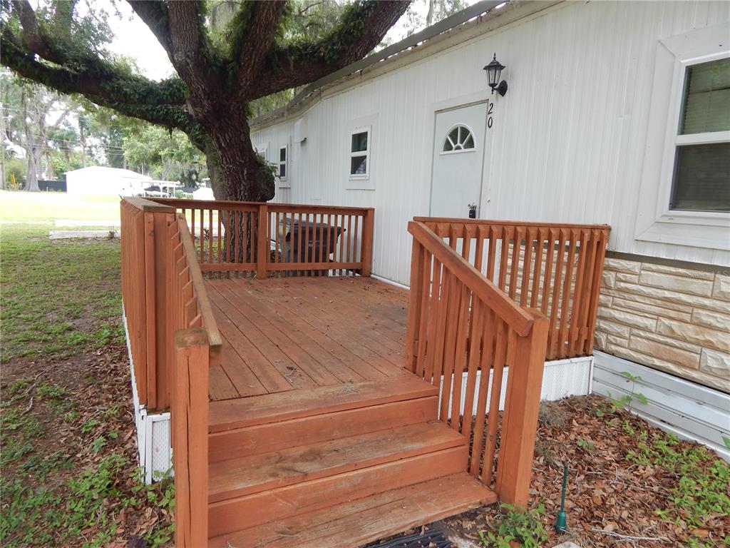 A wooden deck with stairs leads to the white exterior door of a mobile home — 19 ANCHOR INN ROAD, LAKE WALES, FL