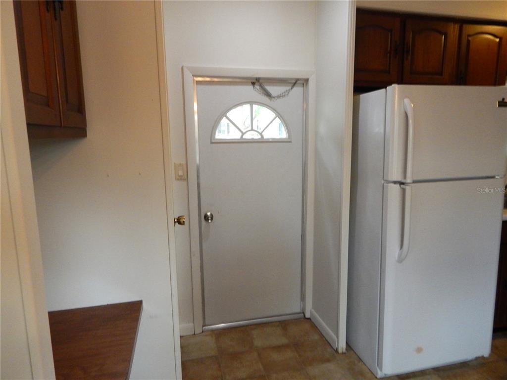 A kitchen features a white door with a fanlight window next to a white refrigerator — 19 ANCHOR INN ROAD, LAKE WALES, FL