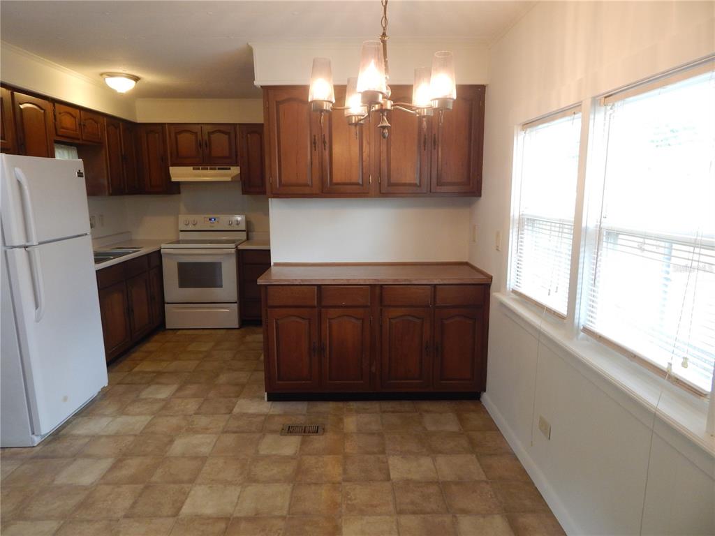 A kitchen with wood cabinets, white appliances, a chandelier, and tiled flooring — 19 ANCHOR INN ROAD, LAKE WALES, FL