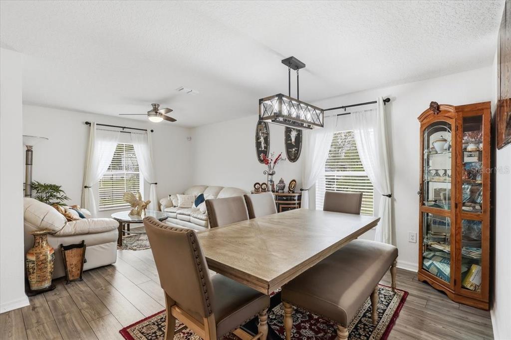 A dining area with a wooden table and bench sits adjacent to a living room — 24 BUD FIELD DRIVE, PALM COAST, FL