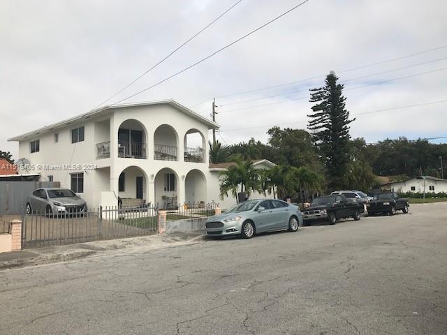 A two-story white house with arched balconies and a fenced yard sits on a street — 1355 SW 12th St, Miami FL 33135, MIAMI, FL