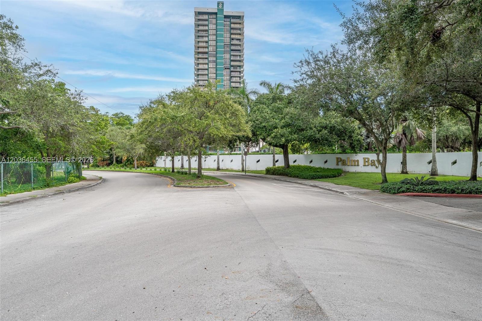A paved road leads toward a tall residential tower behind a Palm Bay sign — 780 NE 69th St # 1010, Miami FL 33138, MIAMI, FL