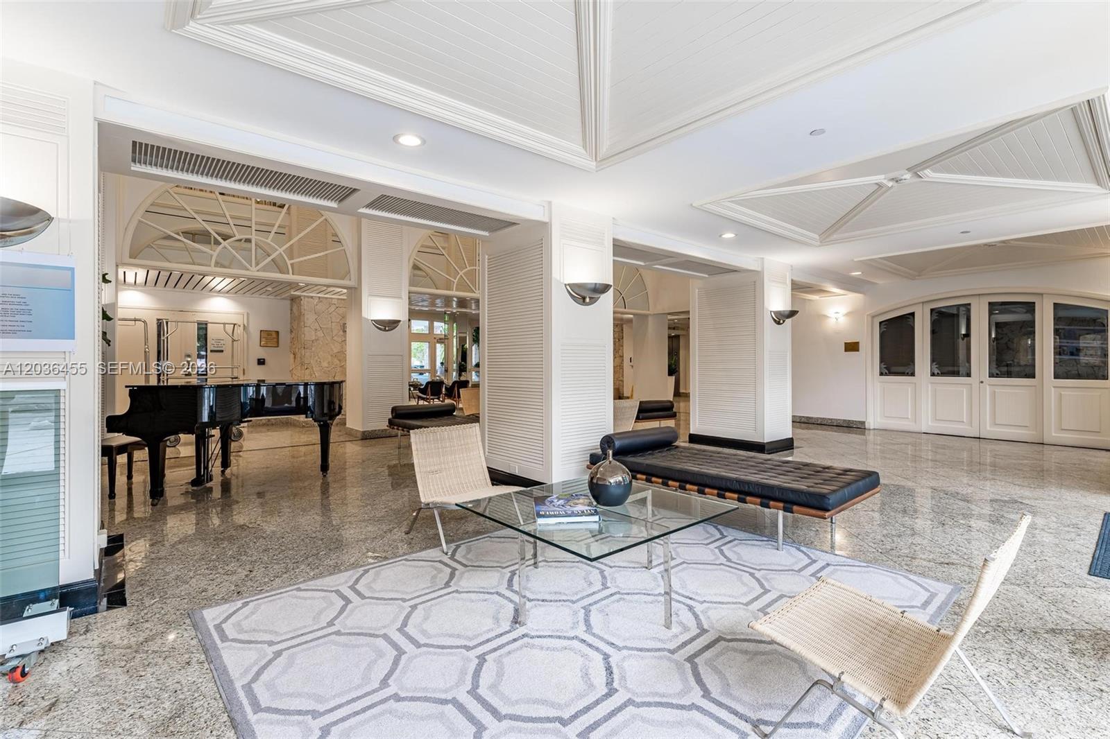 A spacious lobby features a grand piano, modern seating, a glass coffee table, and tile flooring — 780 NE 69th St # 1010, Miami FL 33138, MIAMI, FL
