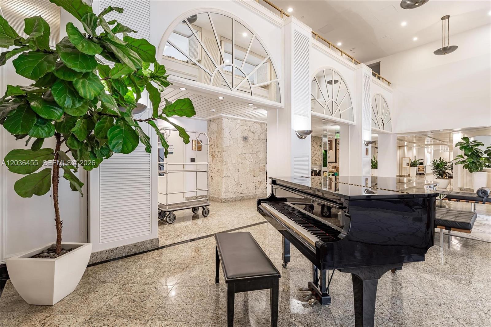 A grand piano sits in a bright, marble-floored lobby featuring arched windows and large plants — 780 NE 69th St # 1010, Miami FL 33138, MIAMI, FL