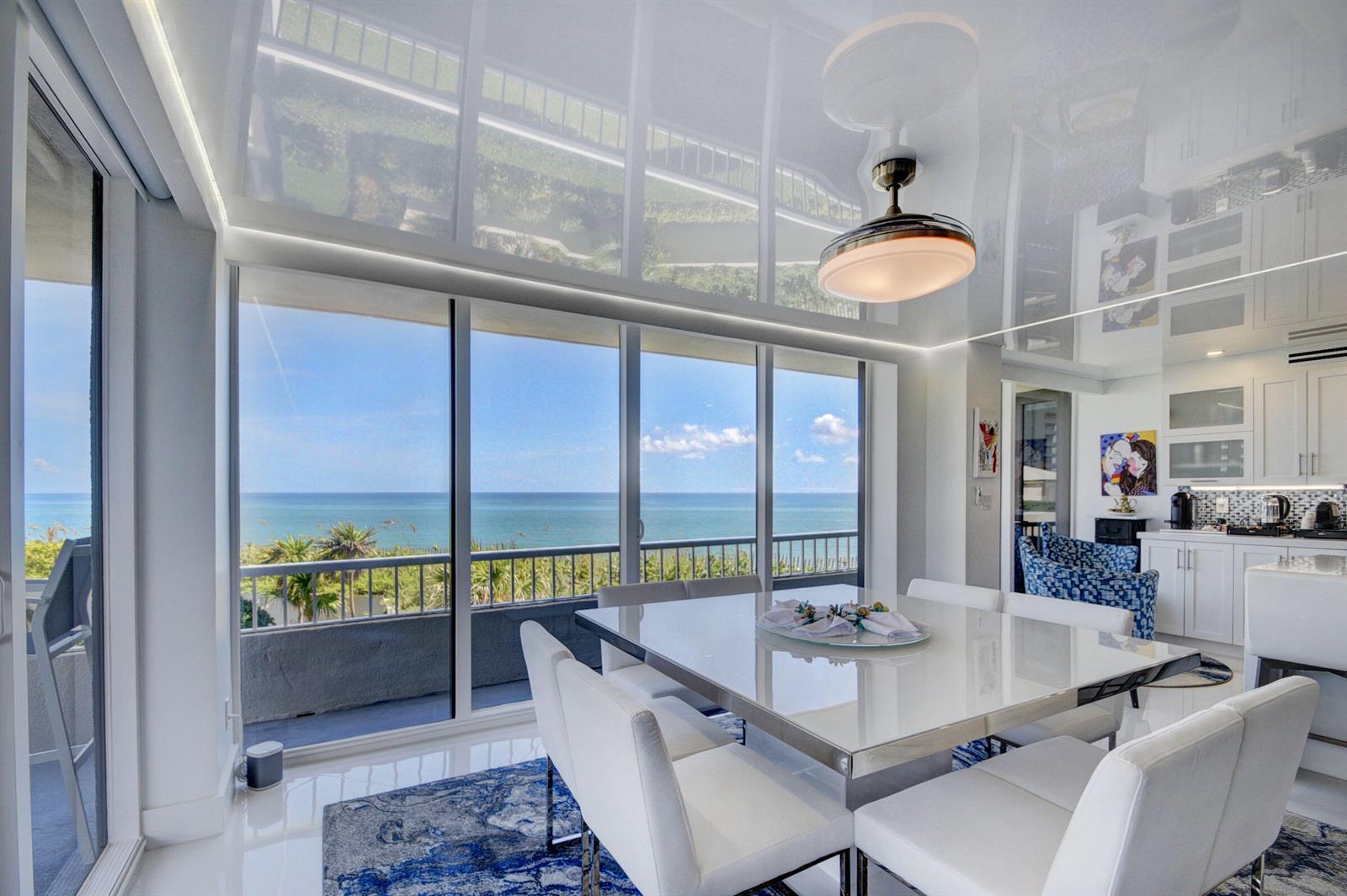 A dining room with a glossy ceiling, white furniture, and a balcony overlooking the ocean — 5510 N Ocean Drive # 2c, Singer Island FL 33404, SINGER ISLAND, FL