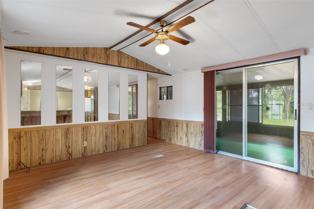 A living room features wood paneling, mirrored wall panels, a ceiling fan, and sliding glass doors — 6463 W PARK DRIVE, HOMOSASSA, FL