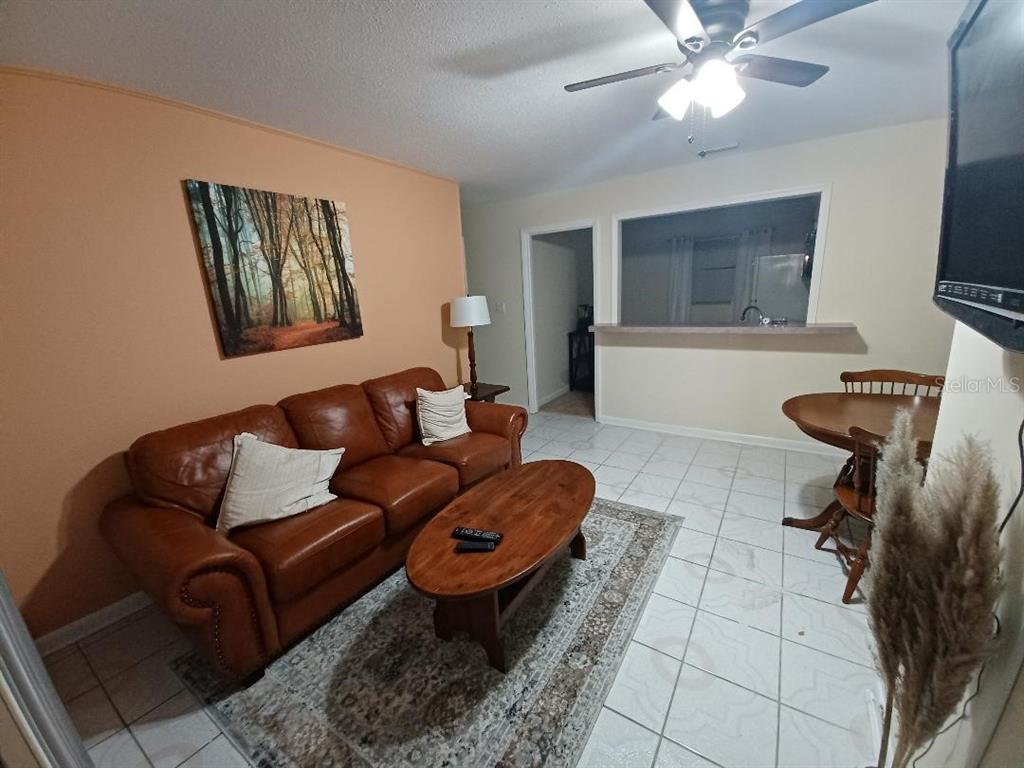 A living room features a brown leather sofa, wood coffee table, and tile flooring — 1942 CONIFER COURT, WINTER PARK, FL