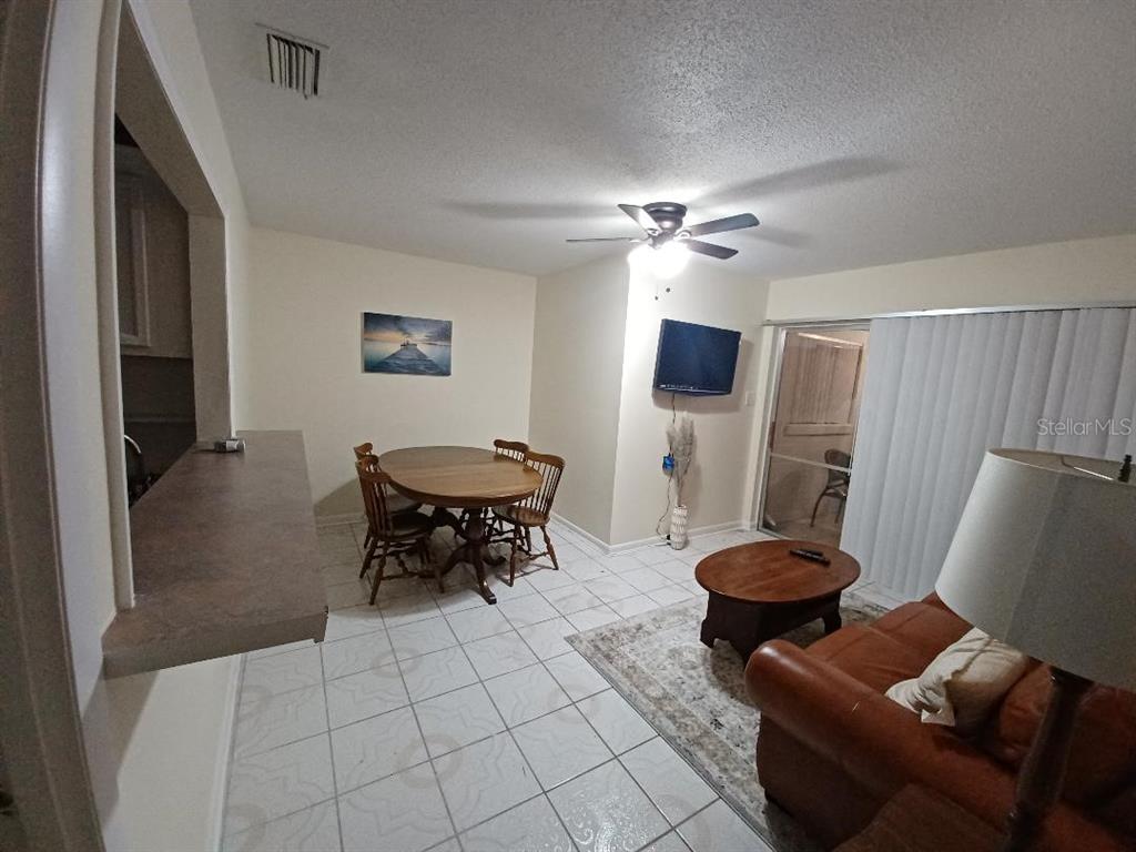An open-concept living and dining area features tile flooring, a ceiling fan, and sliding doors — 1942 CONIFER COURT, WINTER PARK, FL