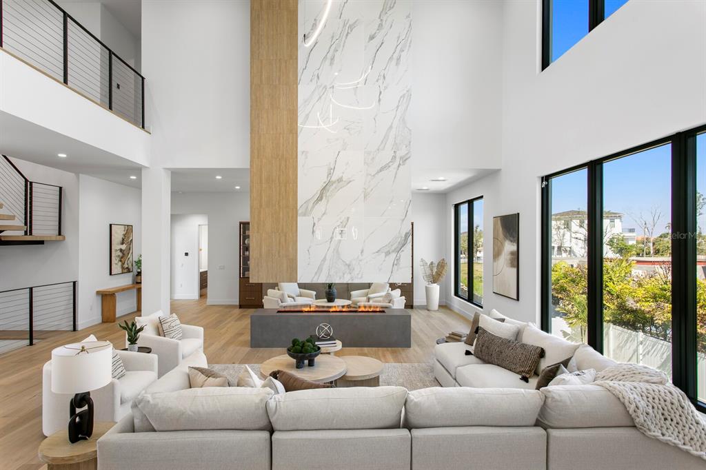 A spacious living room features a double-height ceiling, a marble fireplace, and large windows — 5023 W LEONA STREET, TAMPA, FL