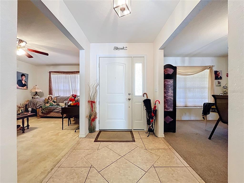 A tiled entryway features a white front door with a side light and adjacent living areas — 4372 ODIN STREET, SPRING HILL, FL
