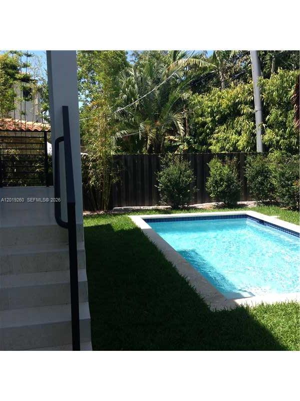 A backyard features a rectangular swimming pool, a patch of grass, and concrete stairs — 472 FERNWOOD DR # 472, Key Biscayne FL 33149, KEY BISCAYNE, FL