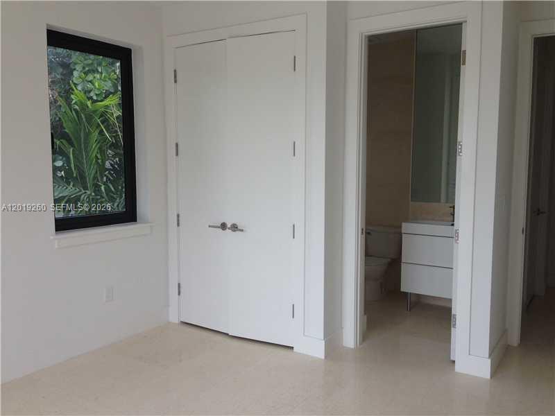 A room with light tile floors, a window, a closet, and an adjacent bathroom — 472 FERNWOOD DR # 472, Key Biscayne FL 33149, KEY BISCAYNE, FL