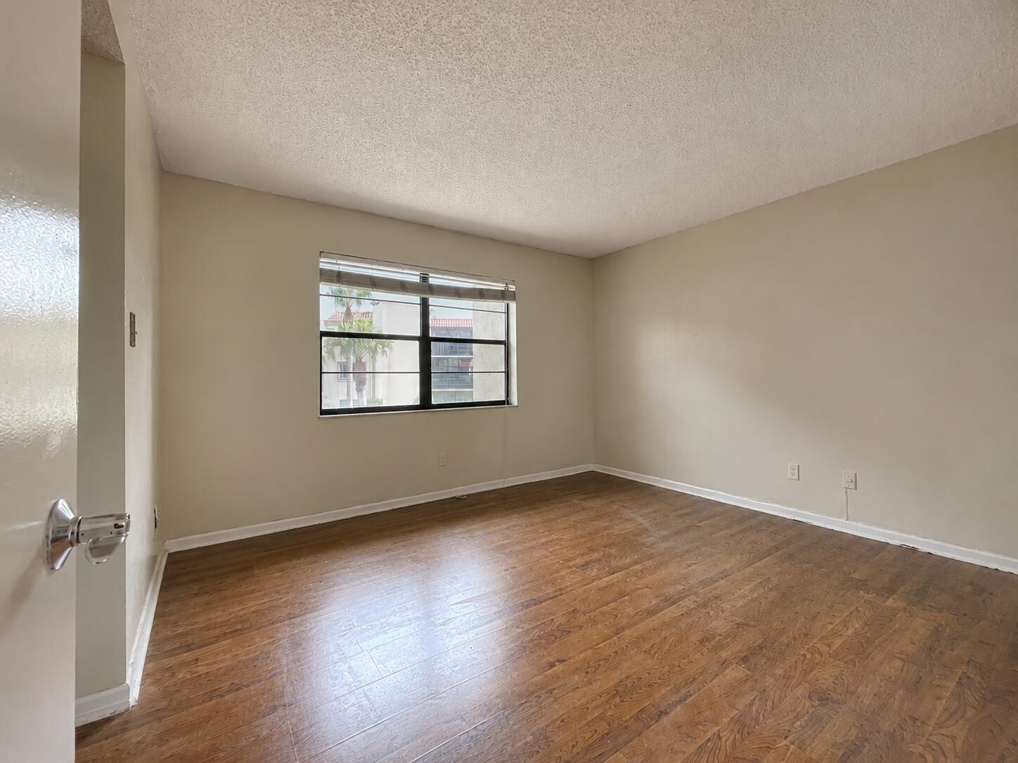 An empty bedroom features light-colored walls, wood-look flooring, and a window with blinds — 2050 Oleander Boulevard # 206, Fort Pierce FL 34950, FORT PIERCE, FL