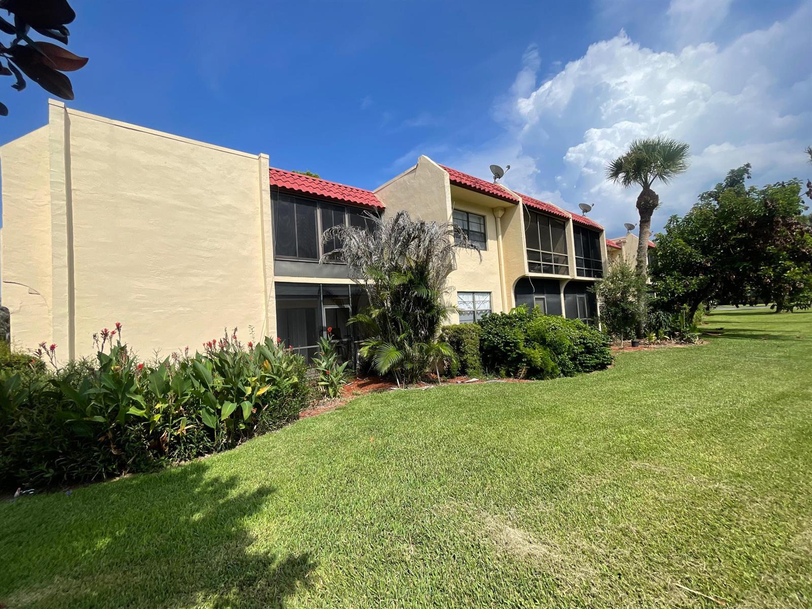 A two-story apartment building with a red tile roof, screened balconies, and landscaped lawn — 2050 Oleander Boulevard # 206, Fort Pierce FL 34950, FORT PIERCE, FL