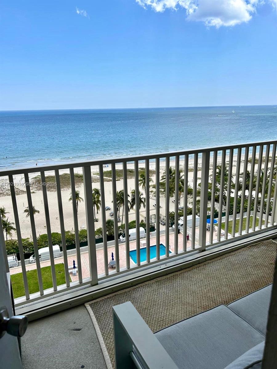 A balcony with a metal railing overlooks a sandy beach, palm trees, and the ocean — 750 N Ocean Blvd # 1106, Pompano Beach FL 33062, POMPANO BEACH, FL