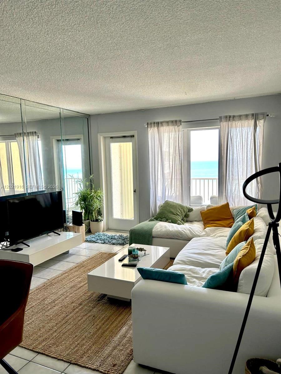 A living room features a white sectional sofa, a coffee table, and ocean views — 750 N Ocean Blvd # 1106, Pompano Beach FL 33062, POMPANO BEACH, FL