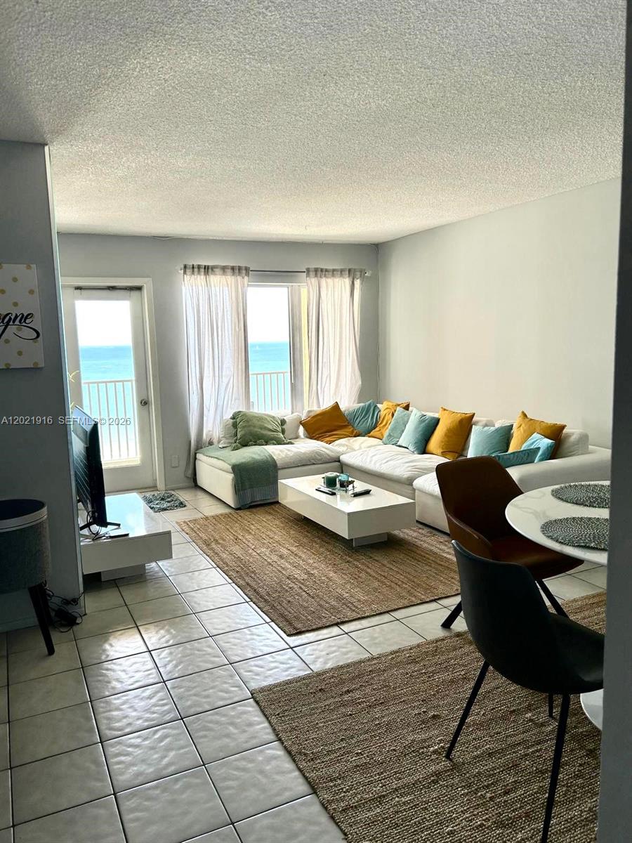 A living room features a white sectional sofa, a coffee table, and ocean views — 750 N Ocean Blvd # 1106, Pompano Beach FL 33062, POMPANO BEACH, FL