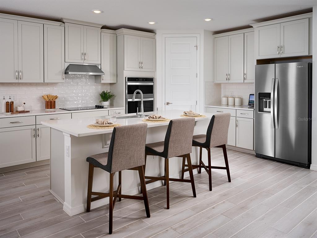 A single-story house with a gray and white exterior, a three-car garage, and landscaping — 13741 UMBER FOREST STREET, HUDSON, FL