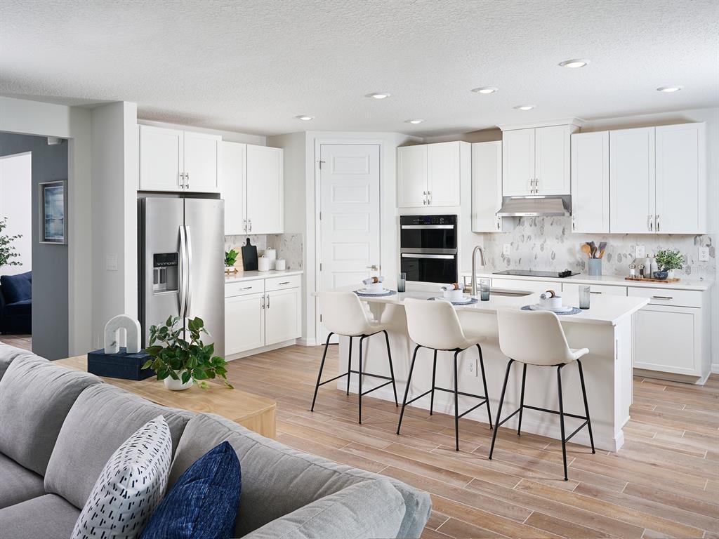 A teal and white single-story house features a three-car garage and a paved driveway — 13741 UMBER FOREST STREET, HUDSON, FL
