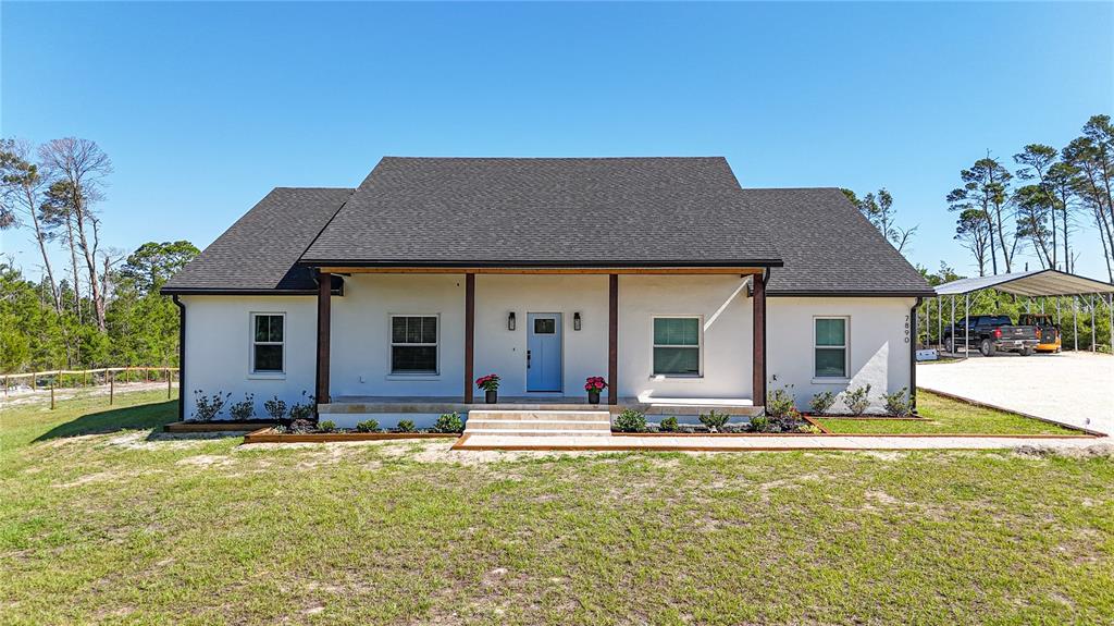 A white single-story house with a dark roof, covered porch, and light blue front door — 7890 SW 129TH AVENUE, CEDAR KEY, FL