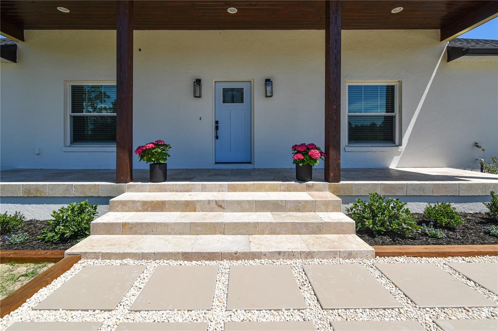 A light blue front door is centered on a covered porch with stone steps — 7890 SW 129TH AVENUE, CEDAR KEY, FL