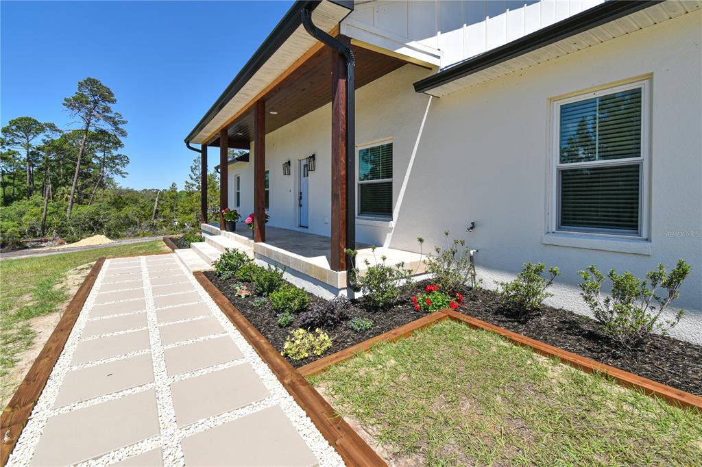 A paved walkway leads to the covered front porch of a white stucco house — 7890 SW 129TH AVENUE, CEDAR KEY, FL