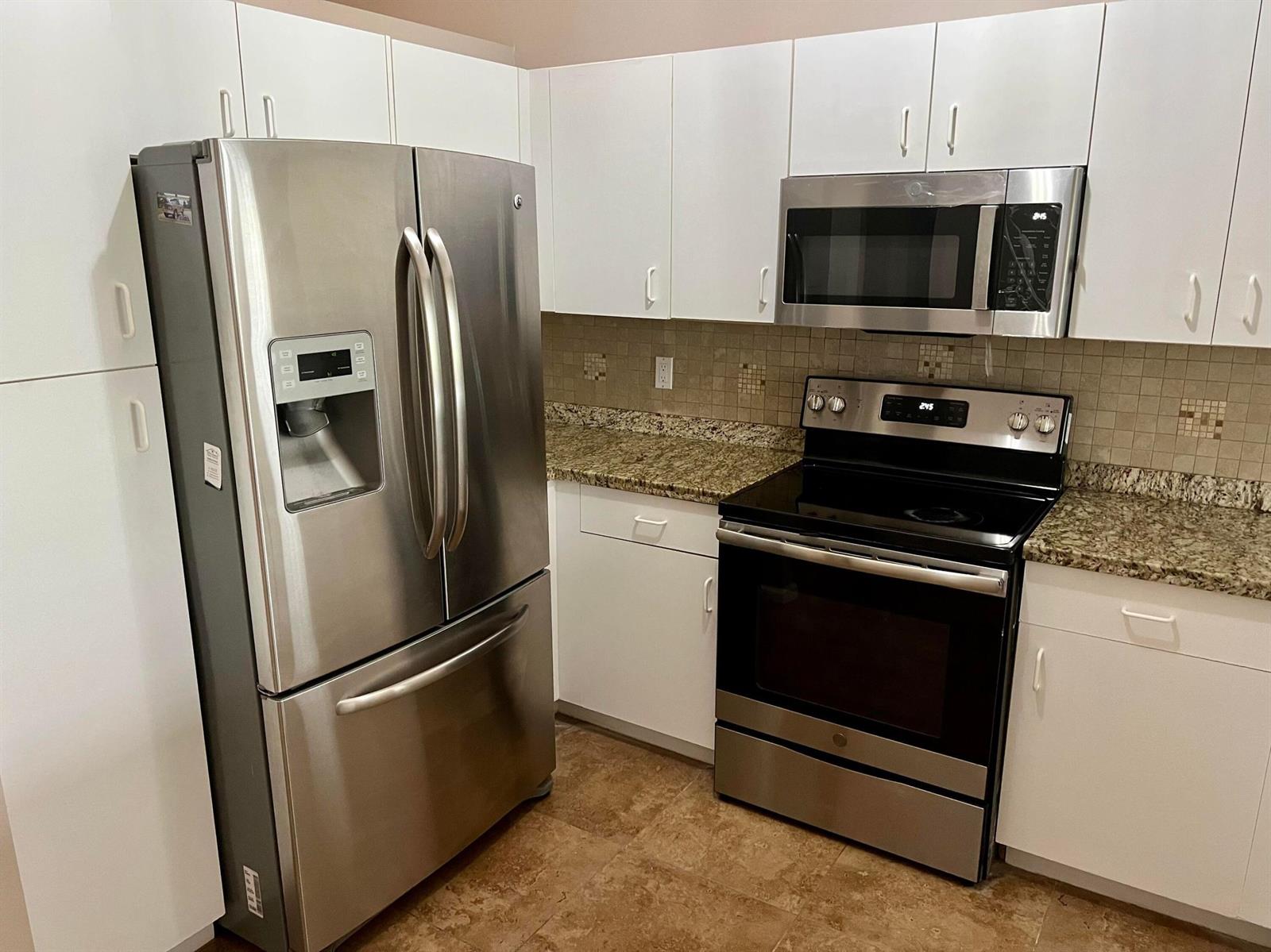 A kitchen features white cabinets, stainless steel appliances, and granite countertops with a tiled backsplash — 6365 Lansdowne Circle, Boynton Beach FL 33472, BOYNTON BEACH, FL