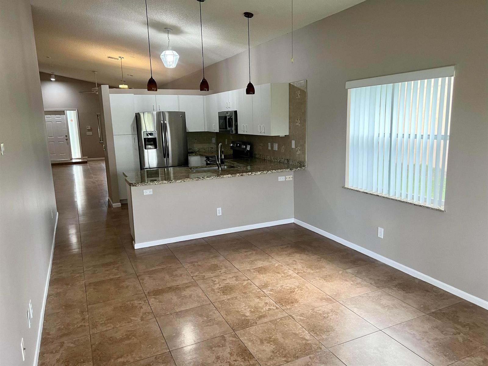 An open-concept kitchen features white cabinets, granite countertops, and tile flooring — 6365 Lansdowne Circle, Boynton Beach FL 33472, BOYNTON BEACH, FL