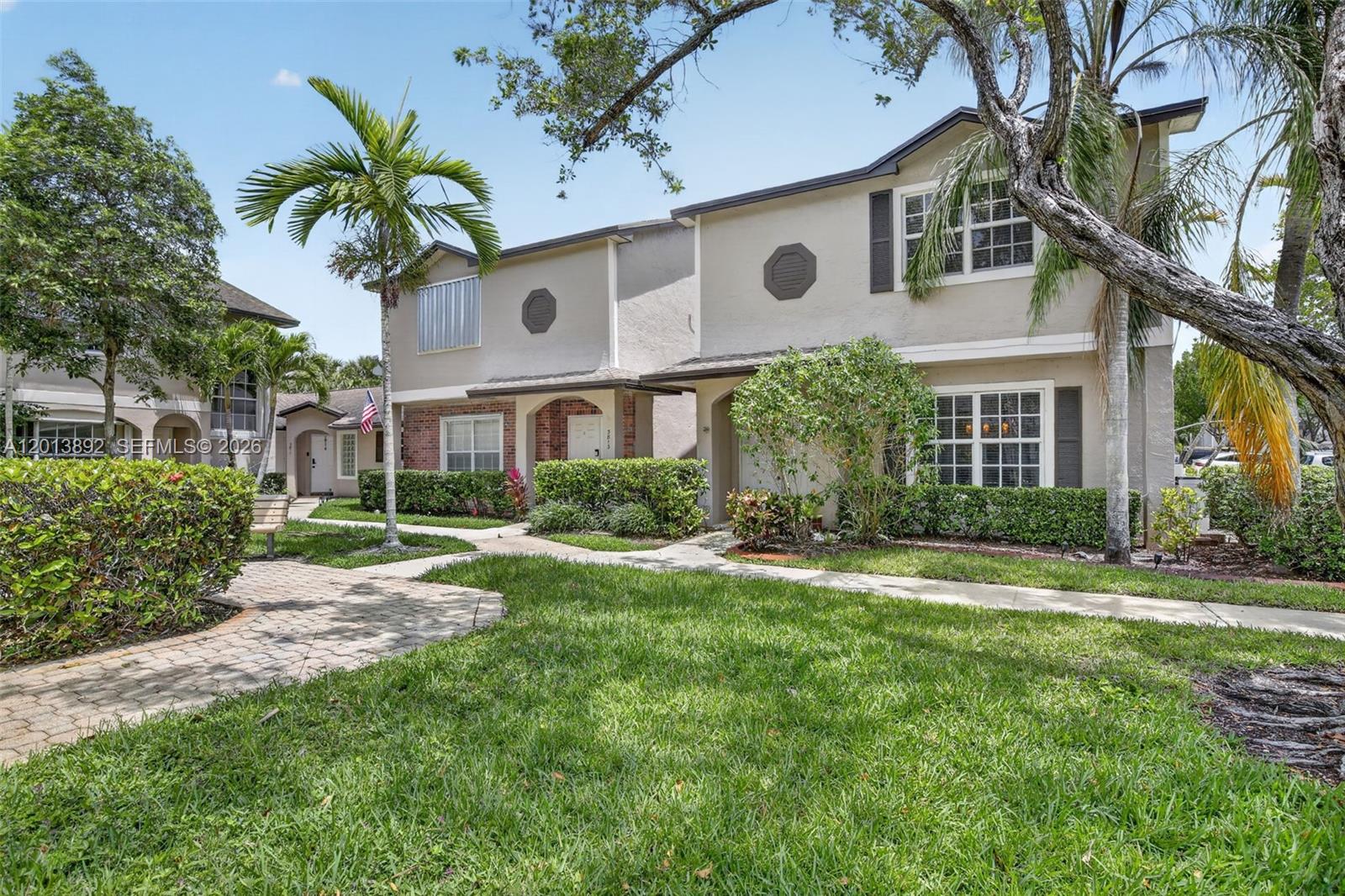 A two-story townhouse with a beige stucco exterior, a brick facade, and a landscaped front yard — 3815 NW 122nd Ter # 3815, Sunrise FL 33323, SUNRISE, FL