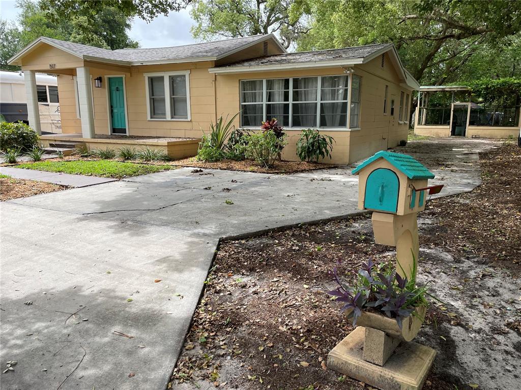 A yellow single-story house with a teal front door and a decorative mailbox in front — 1517 E ELLICOTT STREET, TAMPA, FL