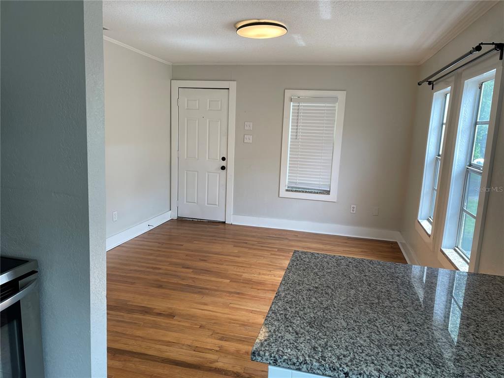 A room with hardwood floors, a white door, a window, and a granite-topped kitchen island — 1517 E ELLICOTT STREET, TAMPA, FL