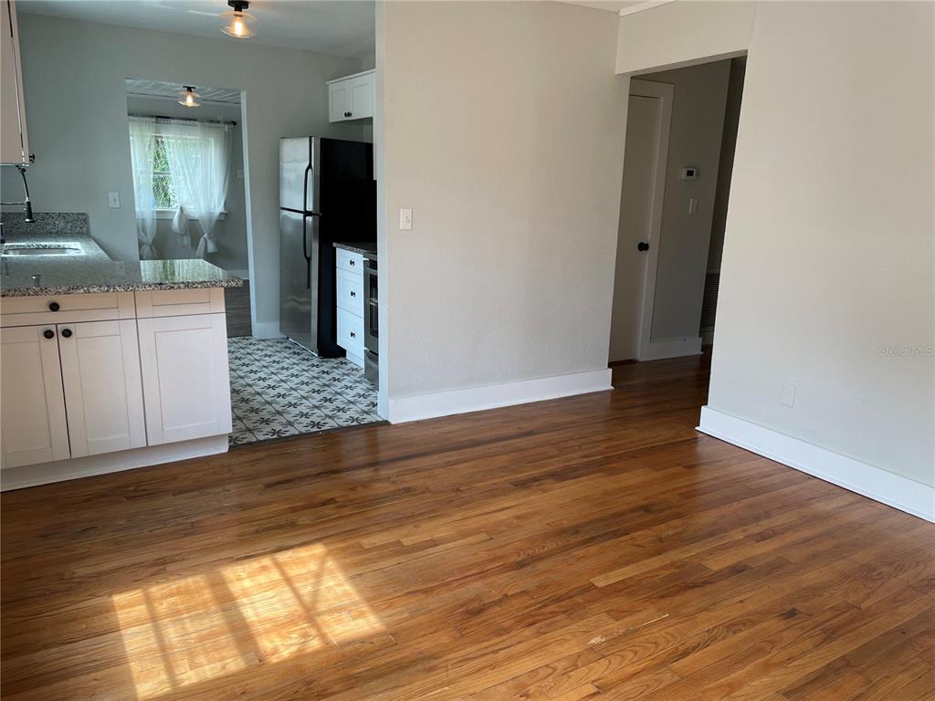 A kitchen with white cabinets and granite countertops opens to a room with hardwood floors — 1517 E ELLICOTT STREET, TAMPA, FL