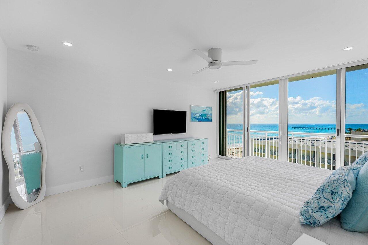 A bedroom with a light blue dresser, oval mirror, and a view of the ocean — 2780 S Ocean Boulevard # 805, Palm Beach FL 33480, PALM BEACH, FL