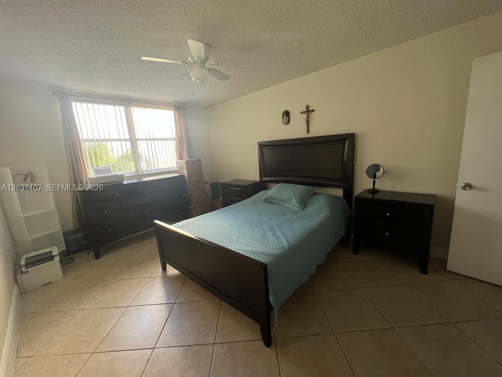 A bedroom features a dark wood bed frame, matching furniture, and light-colored tile flooring — 8215 Lake Dr # 401, Doral FL 33166, DORAL, FL
