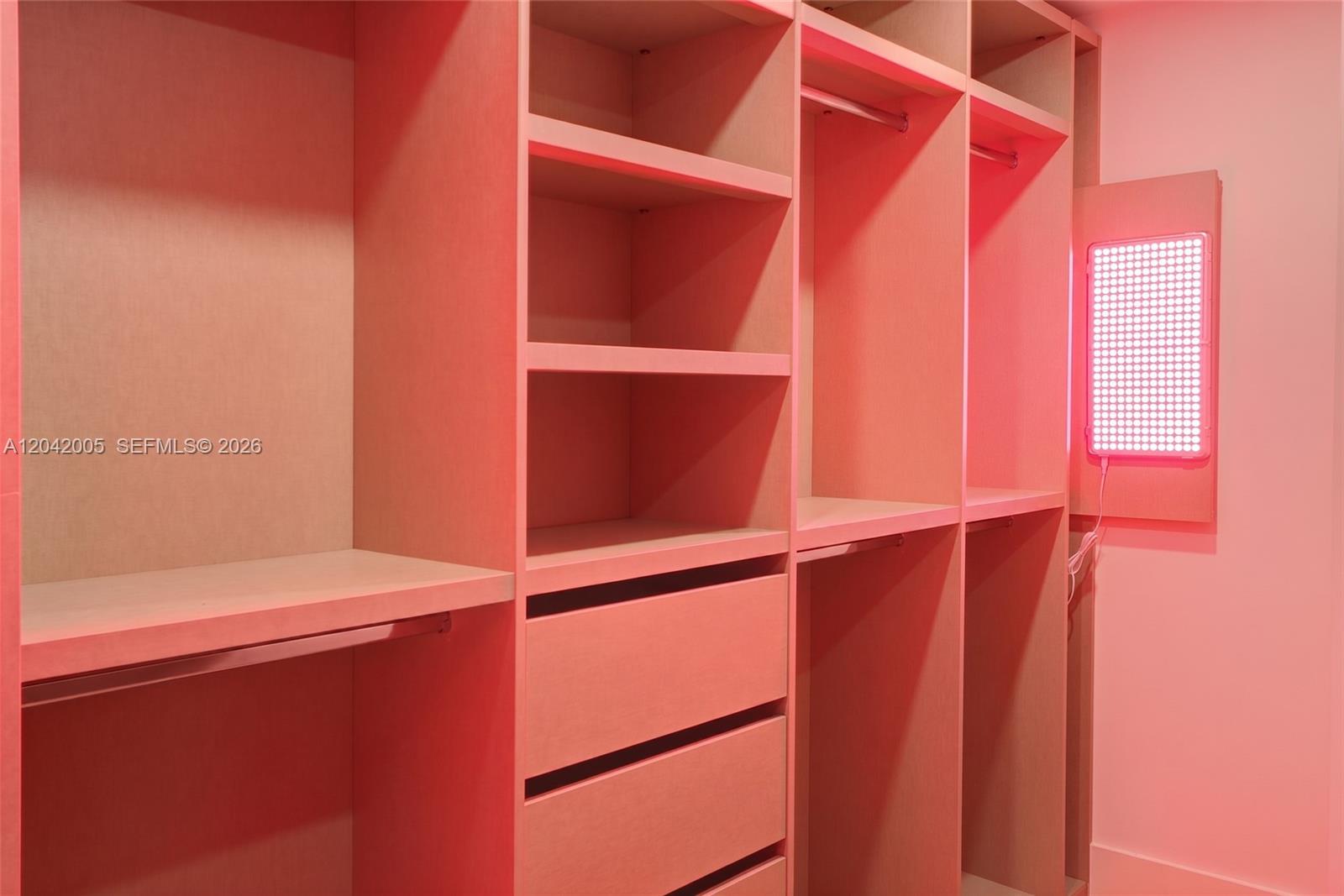 A walk-in closet features light-colored wooden shelving, hanging rods, drawers, and a bright LED panel — 1176 97th St # 703, Bay Harbor Islands FL 33154, BAY HARBOR ISLANDS, FL