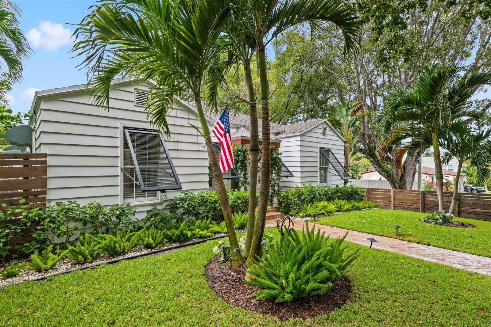 A white, single-story house with horizontal siding, an American flag, and a landscaped front yard — 744 Sunset Road, West Palm Beach FL 33401, WEST PALM BEACH, FL