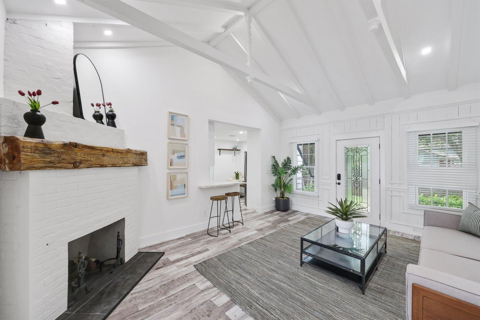A living room features a white brick fireplace, vaulted ceilings, and a glass coffee table — 744 Sunset Road, West Palm Beach FL 33401, WEST PALM BEACH, FL