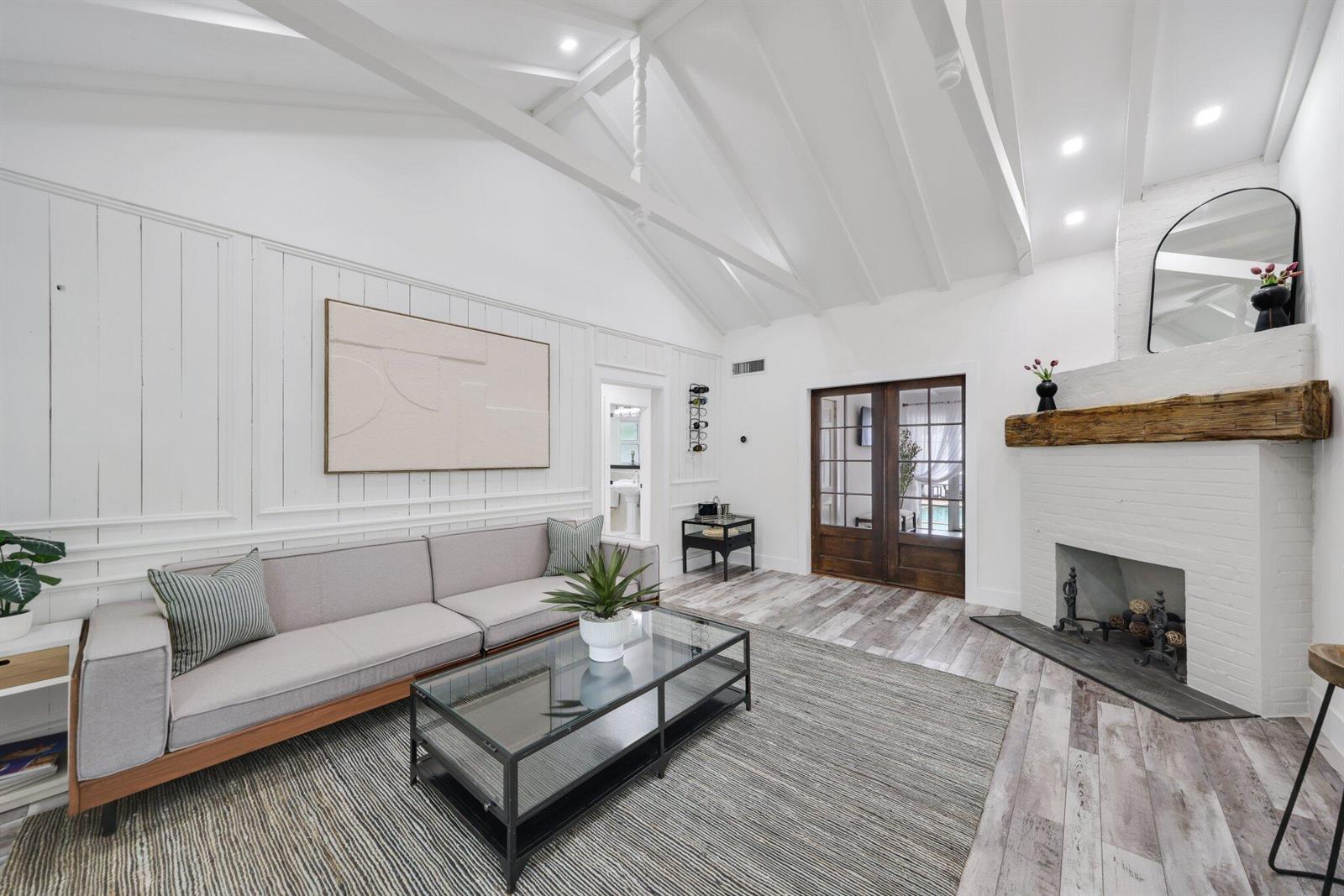 A living room features a vaulted ceiling, white paneled walls, a fireplace, and wood flooring — 744 Sunset Road, West Palm Beach FL 33401, WEST PALM BEACH, FL