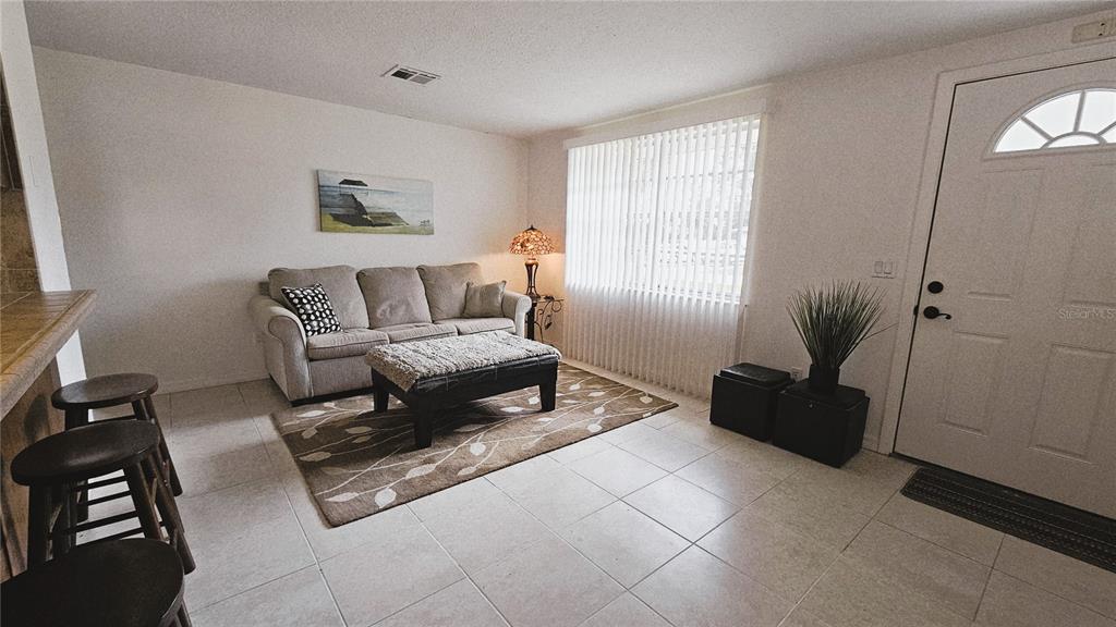 A living room features tile flooring, a beige sofa, a patterned rug, and a front door — 787 LIBERTY STREET, ENGLEWOOD, FL