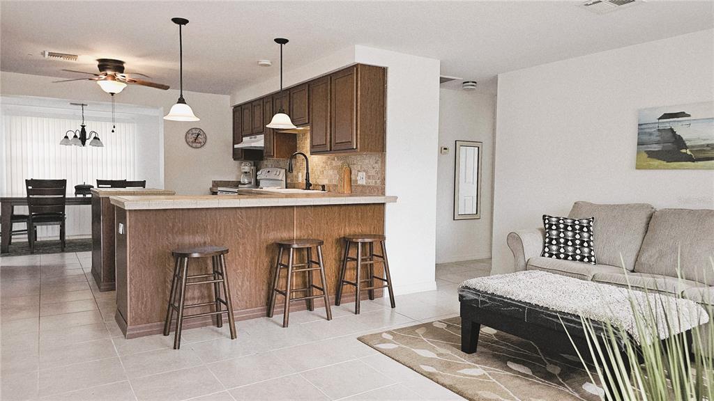 A kitchen with wood cabinets and a breakfast bar overlooks a living room area — 787 LIBERTY STREET, ENGLEWOOD, FL