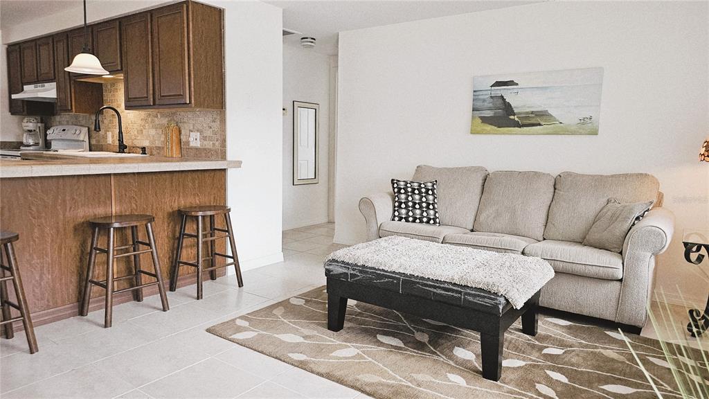 A living room with a beige sofa and ottoman sits adjacent to a kitchen counter — 787 LIBERTY STREET, ENGLEWOOD, FL