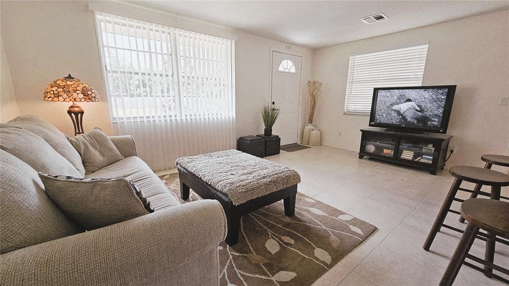 A living room features a sofa, ottoman, television on a stand, and tile flooring — 787 LIBERTY STREET, ENGLEWOOD, FL