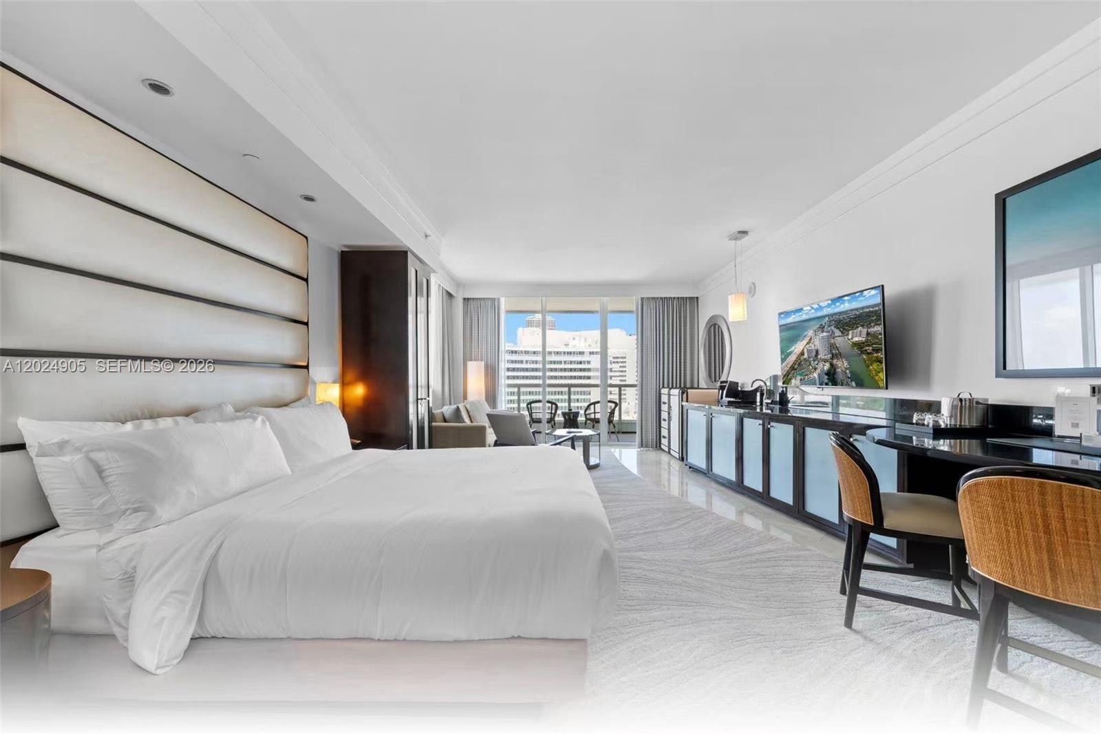 A modern hotel bedroom features a large bed, a desk, and a balcony with city views — 4391 Collins Ave # 1001, Miami Beach FL 33140, MIAMI BEACH, FL